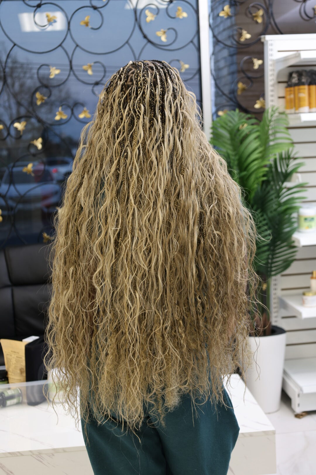 The back of a full head of long blonde miracle knot braids falling past the waist
