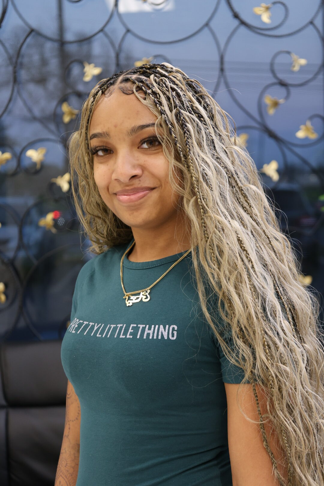 A client with waist-length blonde miracle knot braids, front view, in front of the gold butterfly window at Jalia Walda Salon