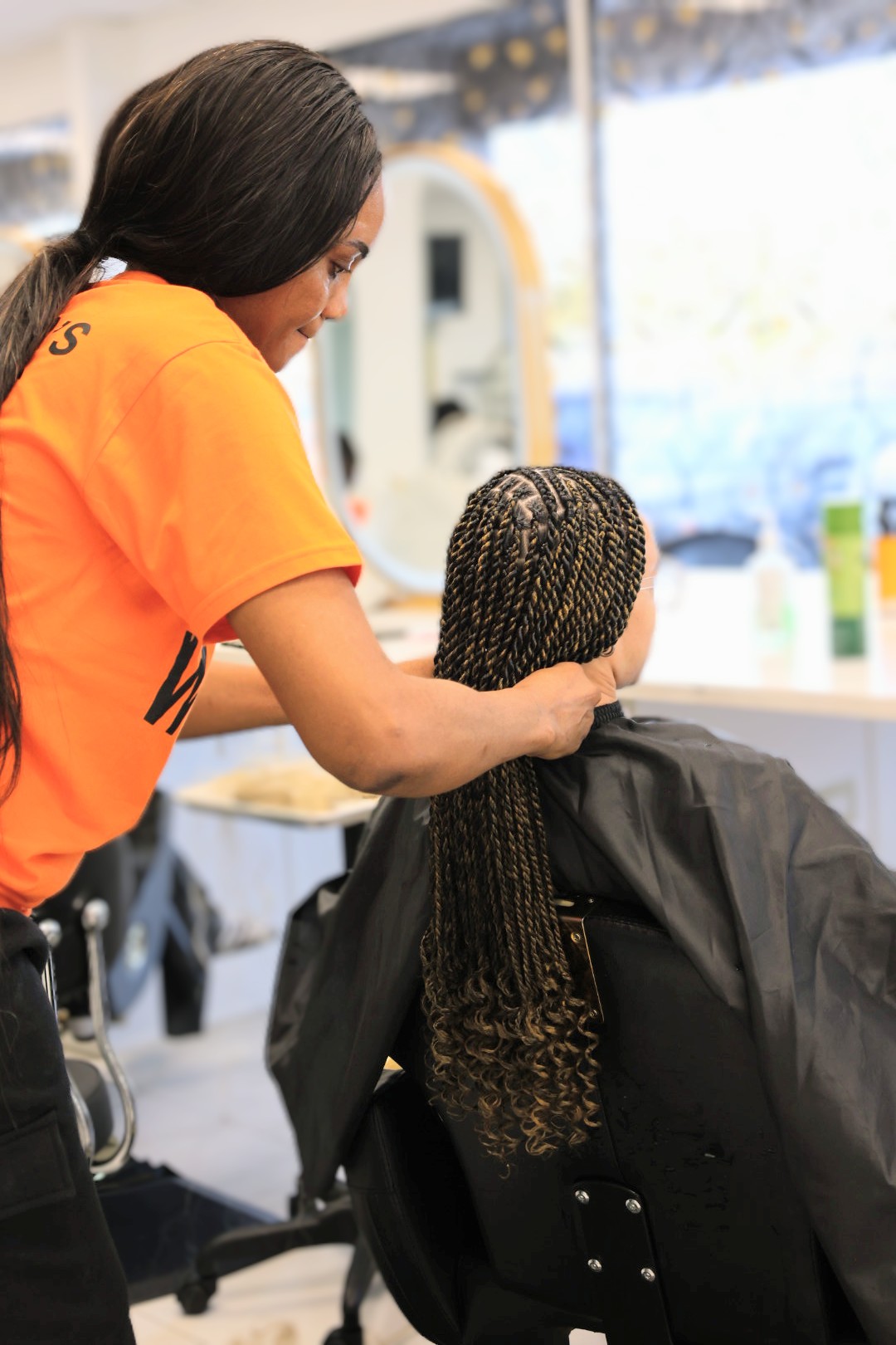 A braider at Jalia Walda Salon twisting a client's hair in the chair