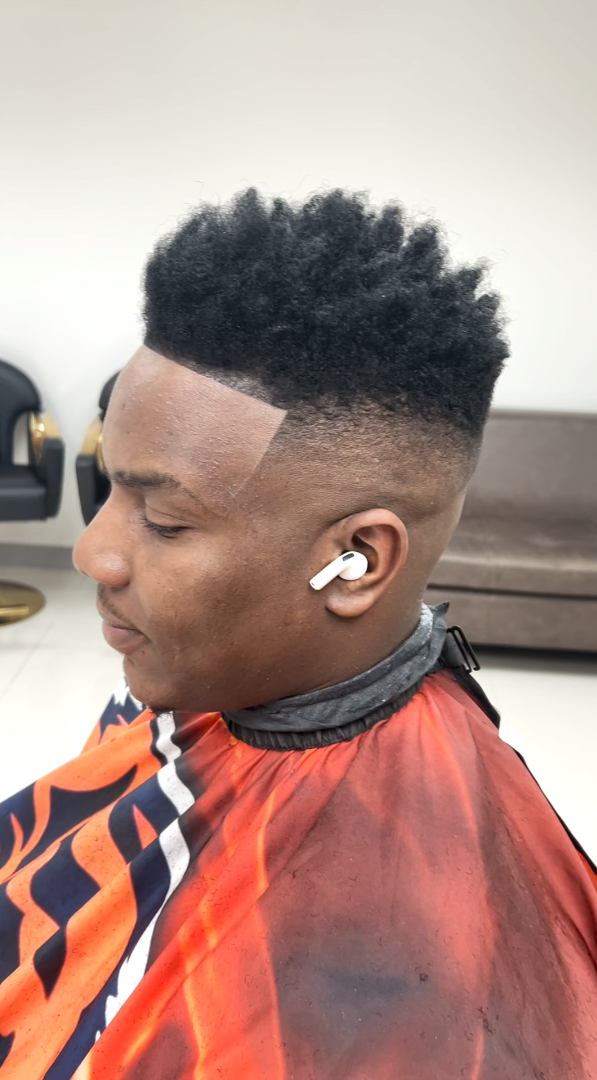 A high-top afro with a taper fade and a crisp squared line-up at the temple