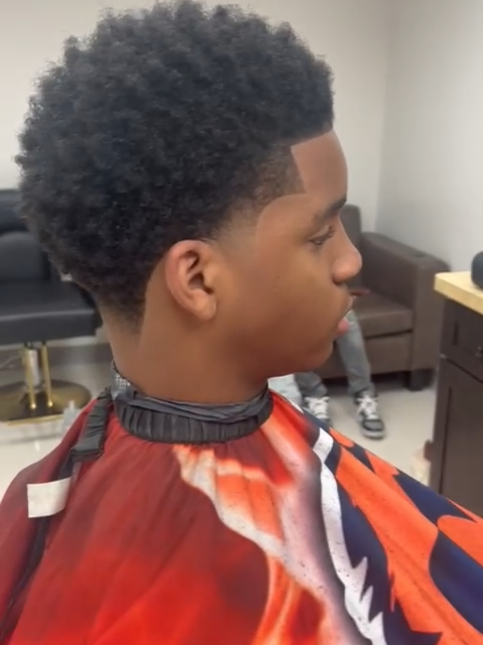 A finished taper fade on a high-top afro seen from behind, with a sharp line-up at the temple