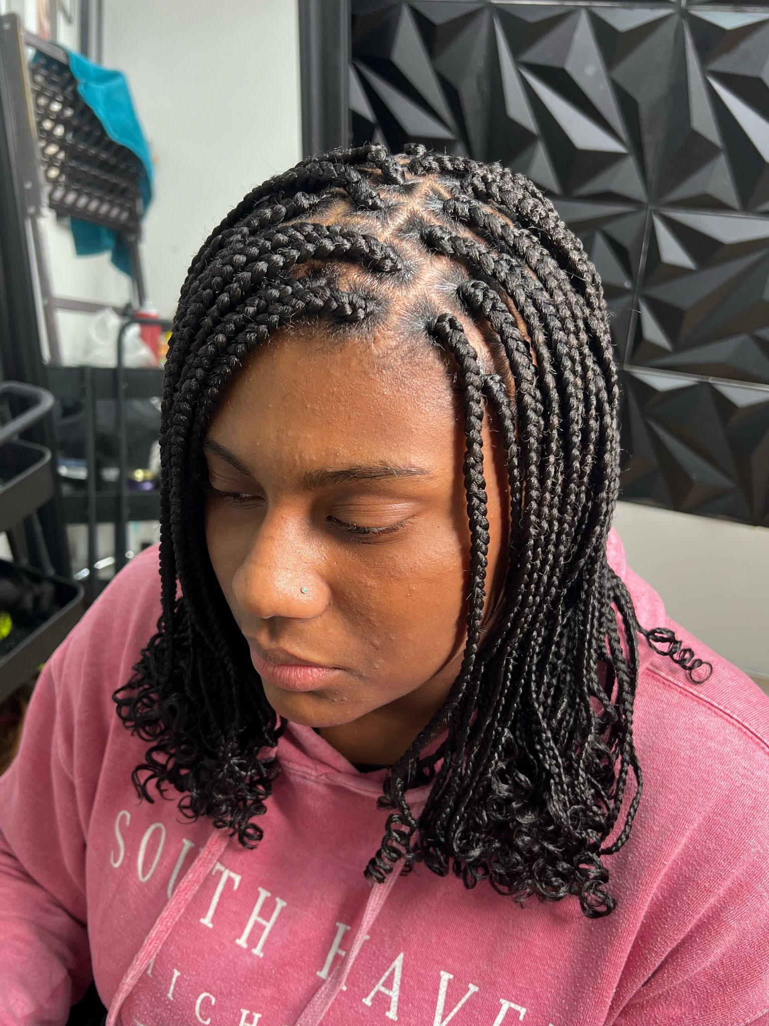 Shoulder-length black box braids with a clean square parting grid across the crown and curled tips
