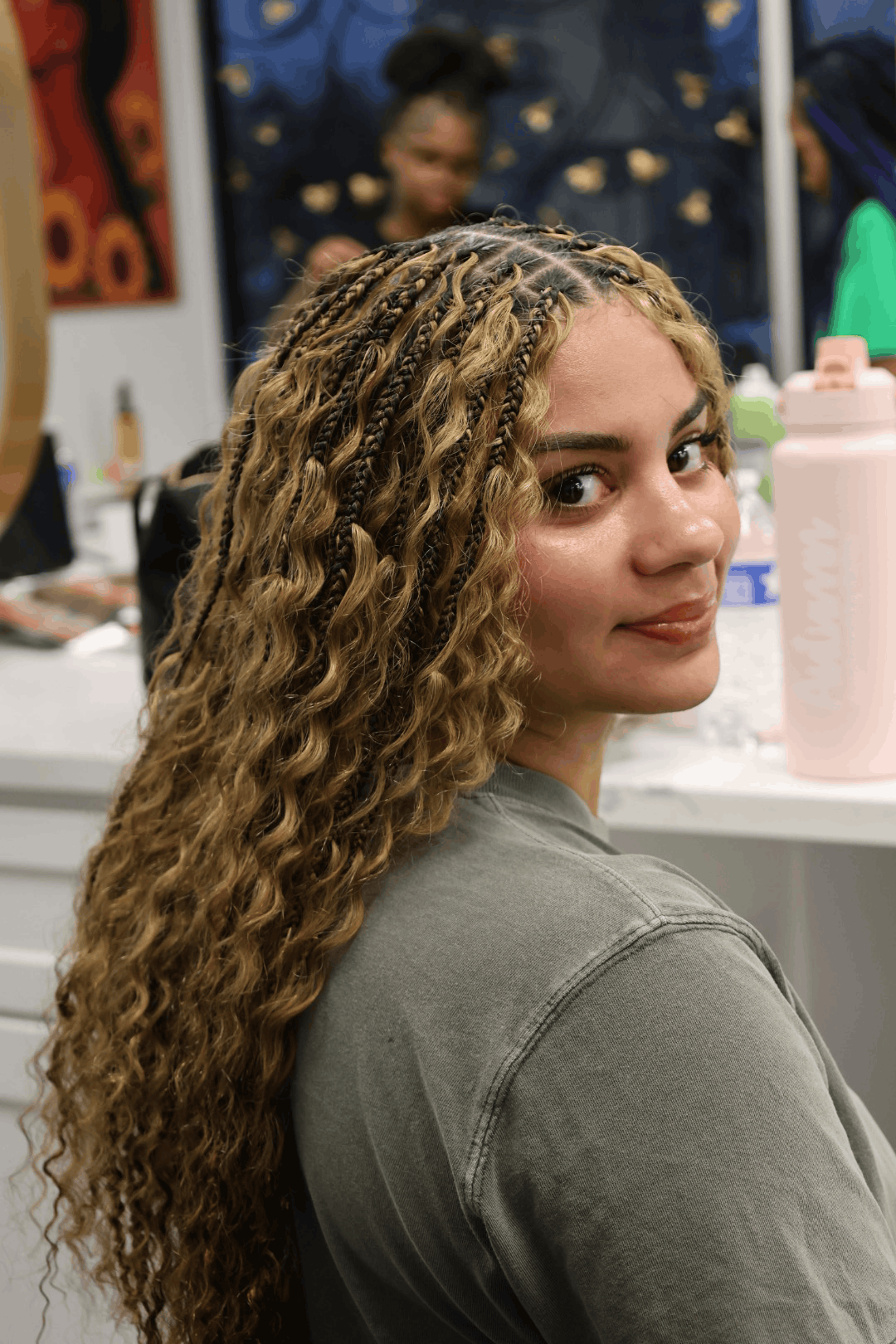 Honey blonde boho braids from the side, showing the parting grid at the crown and curls through the lengths