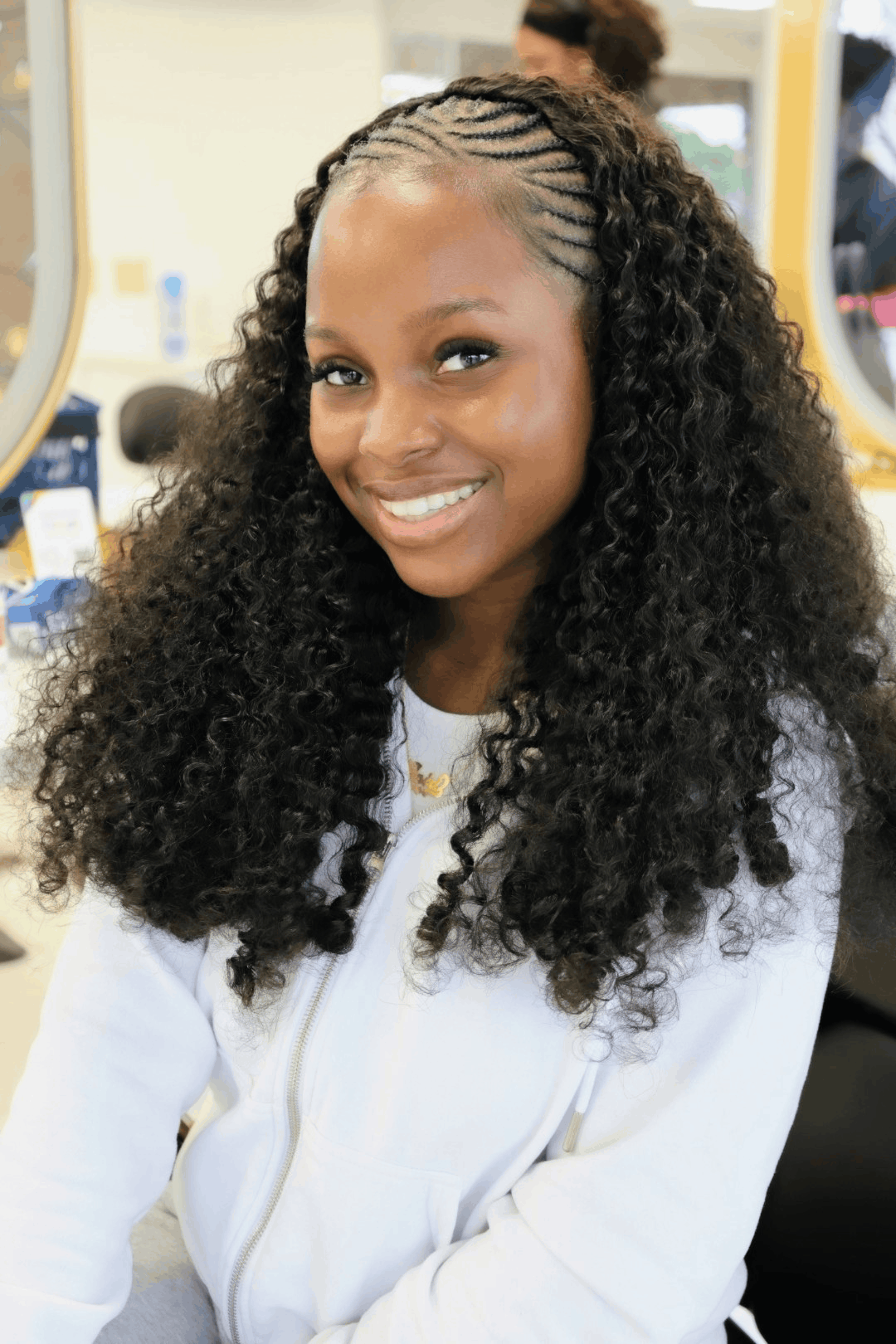Fulani tribal weaves — fine side cornrows at the crown blending into long curly weave lengths, at Jalia Walda Salon in Houston, TX