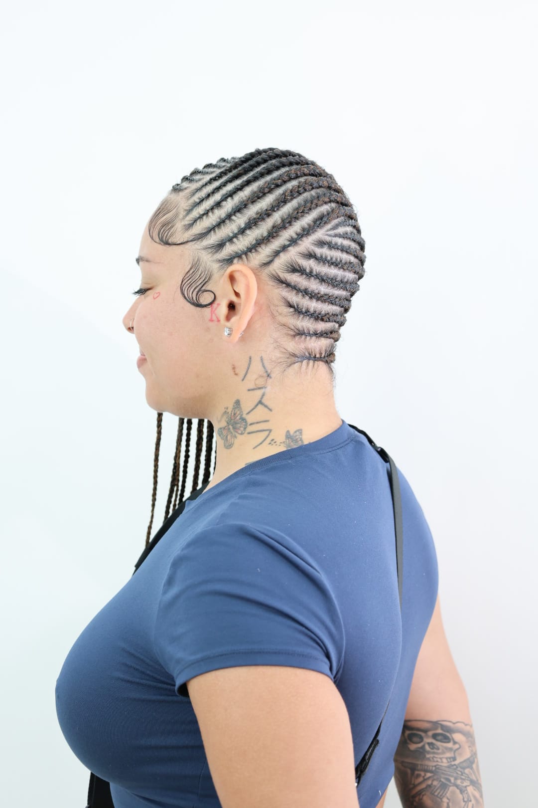 Lemonade braids seen in profile, curved feed-in cornrows swept to one side with the lengths falling over the shoulder